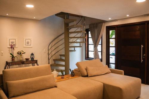 ein Wohnzimmer mit einem Sofa und einer Wendeltreppe in der Unterkunft Sitio Cantinho da Vovó Cida e Vovô Nilson in São João Batista