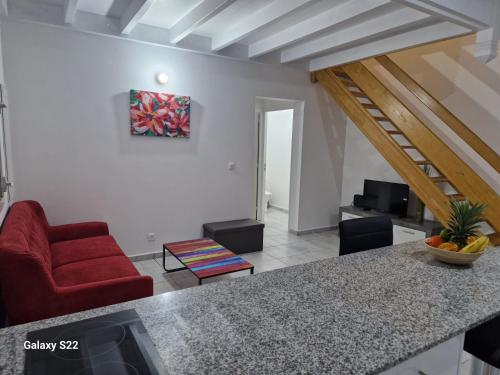 a living room with a red chair and a table at Villa COEUR KERA in Les Abymes