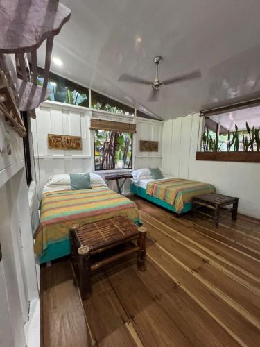 two beds in a room with wooden floors and windows at Caribbean Flow in Puerto Viejo