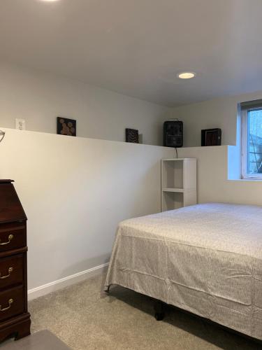 a bedroom with a bed and a dresser and a window at Homestay Basement Falls Church in Falls Church