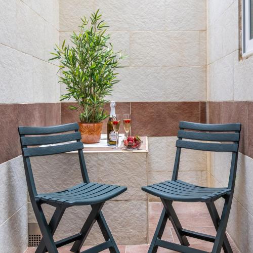 two blue chairs sitting next to a table with glasses of wine at Seafront apartment in Ta'Xbiex in Msida