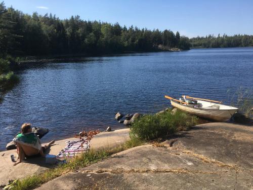 a woman sitting on the shore of a lake with a boat at Boamark Sweden in Mörrum