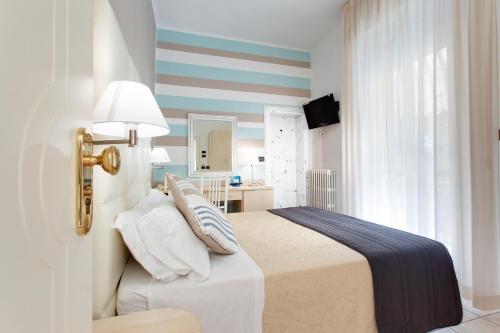 a bedroom with a bed with pillows on it at Hotel Flora in Milano Marittima