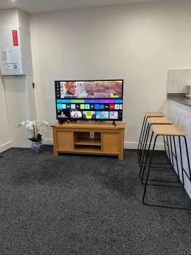 a flat screen tv sitting on top of a wooden entertainment center at The Homely Retreat Spacious Ground Floor Flat Near Oxford City Centre, Free Parking in Oxford