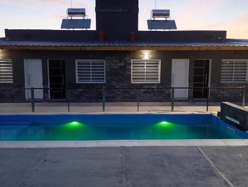 una piscina con luci verdi di fronte a una casa di Vistas de Victoria - Potrero de los Funes a Potrero de los Funes
