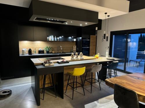 a kitchen with a large island with yellow bar stools at Maison Moderne piscine chauffée in Saint-Hilaire-de-Brethmas