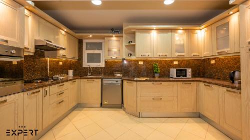 a large kitchen with white cabinets and appliances at The Expert in Ocean Blue Near Airport in Cairo