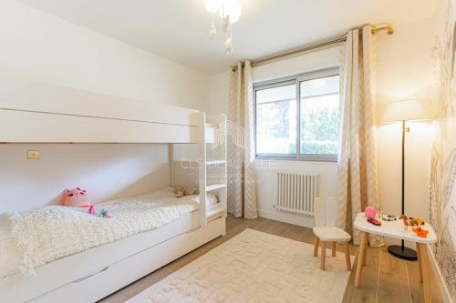 - une chambre blanche avec des lits superposés et une table dans l'établissement Azur & Sable Appart de Standing à 100m Mer CLS Deauville, à Benerville-sur-Mer