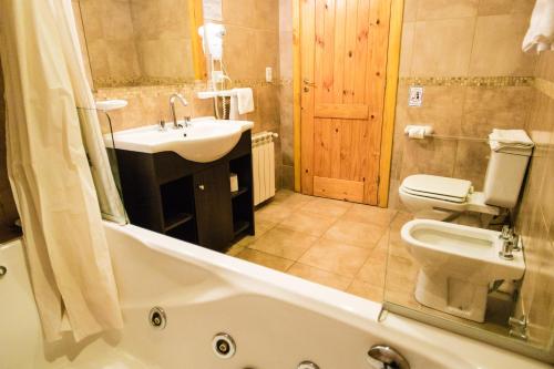 a bathroom with a tub and a sink and a toilet at Encanto del Rio in Villa La Angostura
