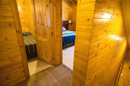 a small room with a bed in a wooden cabin at Encanto del Rio in Villa La Angostura