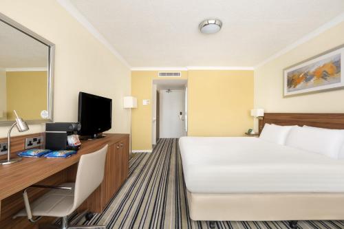 a hotel room with a bed and a desk and a television at Holiday Inn York by IHG in York