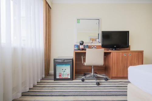 a room with a desk and a chair and a television at Holiday Inn York by IHG in York
