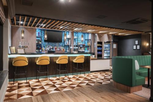 a bar with yellow stools and a tv at Holiday Inn York by IHG in York