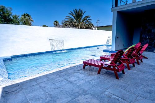 eine Gruppe roter Stühle neben einem Pool in der Unterkunft Casita Nodin in Cuatrociénegas de Carranza