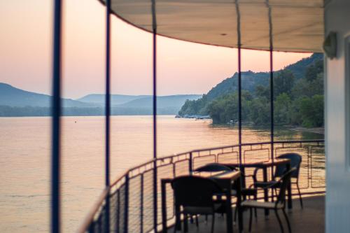 a table and chairs on a balcony overlooking a lake at Aquamarina Hotel Visegrád in Visegrád