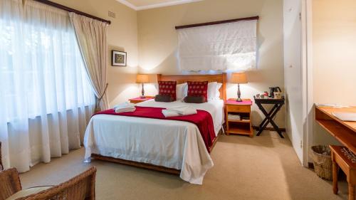 a bedroom with a large bed and a window at Porcupine Ridge Guest House in Sabie