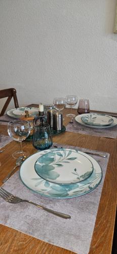 a table with plates and glasses on a wooden table at Le panoramique in Cayeux-sur-Mer