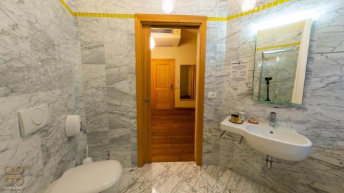 a white bathroom with a sink and a mirror at Residenza d'Epoca Albergo Grimani in Ampezzo