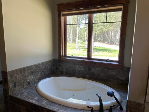 a large bath tub in a room with a window at Woodsy and Private- Dream House on a 7 Acre Pond in Kingsley