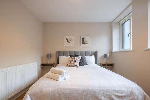 a bedroom with a large white bed with two windows at 2nd Floor Stylish 2-Bed Apartment in Drogheda