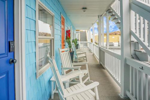 a row of rocking chairs on the porch of a house at The Boardwalk Inn in Carolina Beach