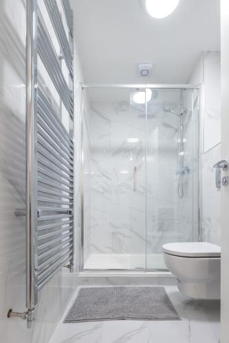 a white bathroom with a shower and a toilet at 3rd Floor Stylish 2-Bed Apartment in Drogheda