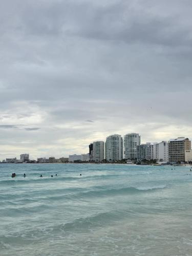 a group of people swimming in the ocean near a city at Cancun Beach & Nightlife Paradise SALVIA CONDOMINIUMS in Cancún