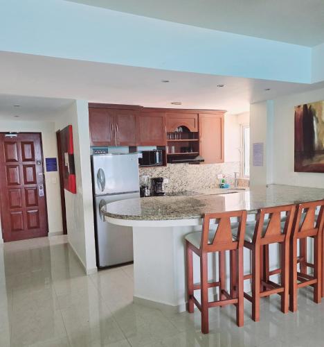 a kitchen with a island with chairs and a counter top at Cancun Beach & Nightlife Paradise SALVIA CONDOMINIUMS in Cancún