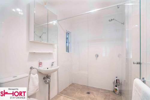a white bathroom with a shower and a sink at King & Queen Bed - Apartment on Summer Near Cook Park in Orange
