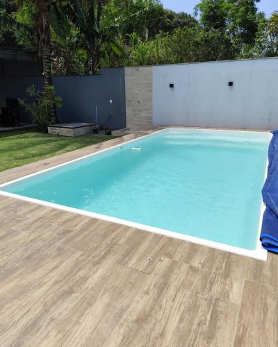 a swimming pool with blue water in a backyard at Casa Praia Reserva - Casa Completa no Paraíso in Aracruz