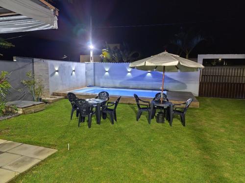 a group of tables and chairs with an umbrella at Casa Praia Reserva - Casa Completa no Paraíso in Aracruz
