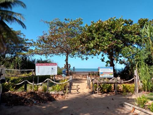 a beach with signs and trees and the ocean at Casa Praia Reserva - Casa Completa no Paraíso in Aracruz