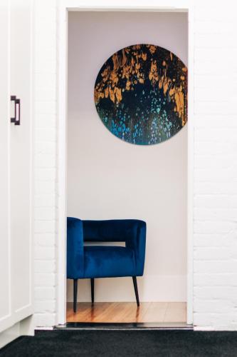 a blue chair in a room with a painting on the wall at The Manor Apartments in Port Lincoln