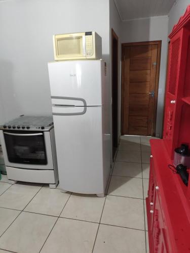 a microwave on top of a refrigerator in a kitchen at Casa Praia Reserva - Casa Completa no Paraíso in Aracruz