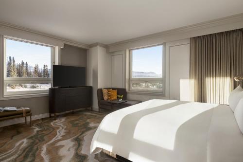 a bedroom with a large white bed and windows at Fairmont Château Lake Louise in Lake Louise