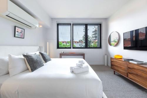 a bedroom with a large white bed and a tv at Welcome To Casa de Richmond in Melbourne