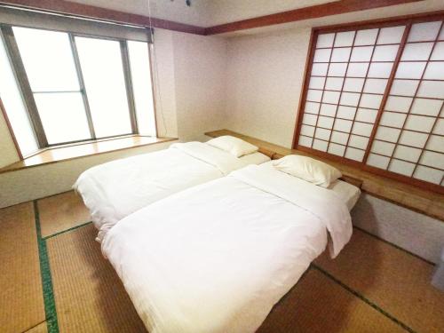 two white beds in a room with two windows at Zamami Chura Dreamz in Zamami