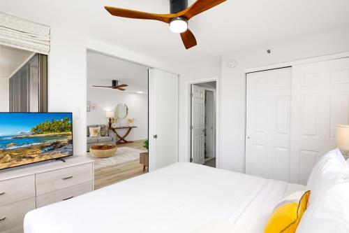 a white bedroom with a white bed and a ceiling fan at Waikiki Banyan Fabulous Ocean View Condo with Free Parking in Honolulu