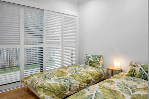 a bedroom with two beds and a window with blinds at Ocean views in Buddina