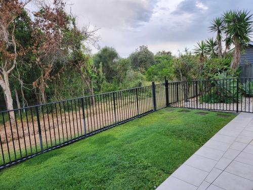 a black fence with a yard of green grass at Ocean views in Buddina