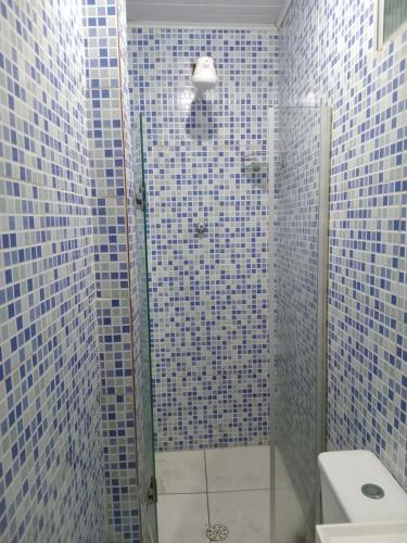 e bagno piastrellato blu con doccia e servizi igienici. di Casinha Duplex na Avenida Centenário com varanda, Ar e Wi-Fi a Salvador