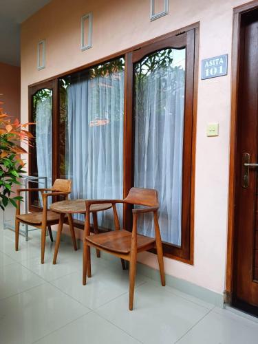 two wooden chairs and a table in front of a window at Astana House in Ubud