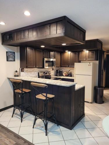a kitchen with wooden cabinets and a counter with bar stools at Little Womens Villa Condo 1 mile from Parkway in Gatlinburg