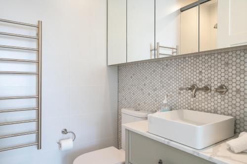 a white bathroom with a sink and a toilet at New Penthouse with Ocean & Golf Course Views in Collaroy