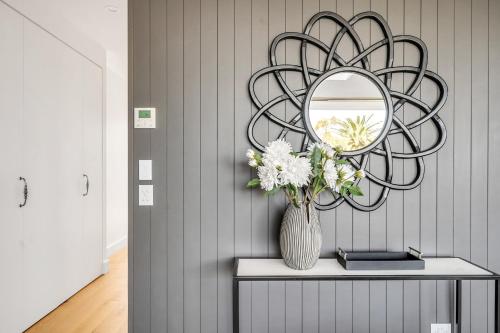 a vase of flowers on a table with a mirror at New Penthouse with Ocean & Golf Course Views in Collaroy