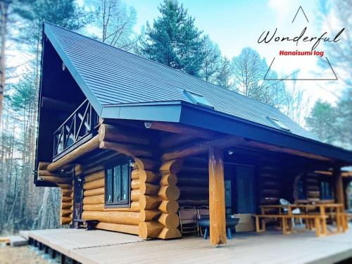 a log cabin with a roof on a wooden deck at 北軽井沢の浅間山麓に佇む本格カラオケとサウナ付きログハウス in Tsumagoi