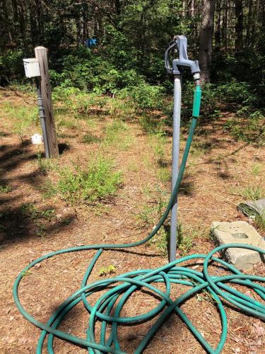a green hose hooked up to a water meter at Woodsy and Private- Rustic Cabin in Kingsley