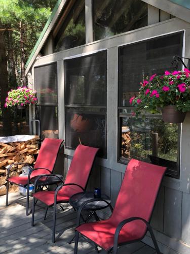 a group of red chairs sitting on a porch at Woodsy and Private- Rustic Cabin in Kingsley