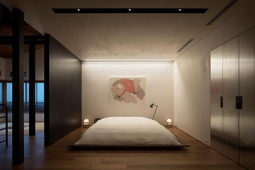 a bedroom with a bed and a painting on the wall at Trunk House in Tokyo