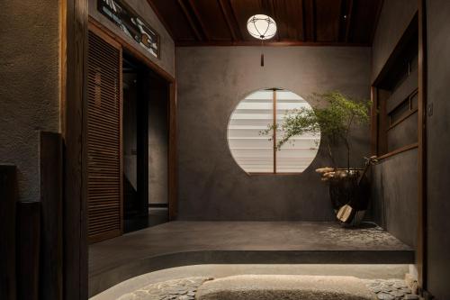 a hallway with a round window and a clock on the wall at Trunk House in Tokyo